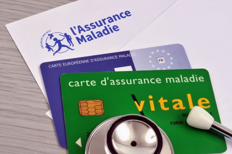 French Carte Vitale, European Health Insurance Card, and Assurance Maladie documents on a desk