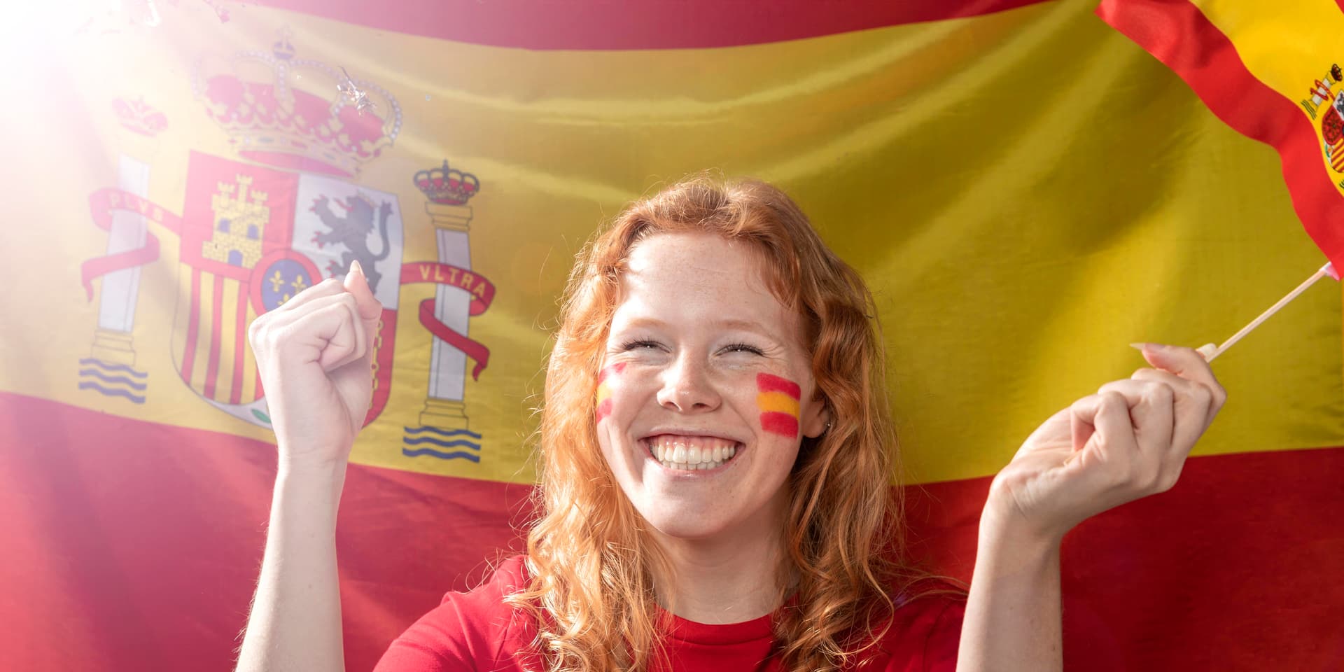 Mujer sonriente sosteniendo una bandera española